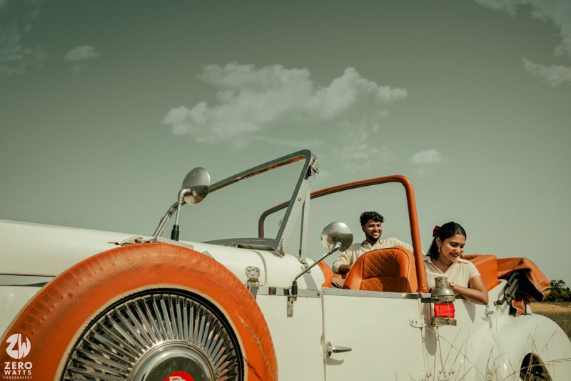 A vintage white convertible car sits parked in a sunny field with a retro-styled aesthetic.