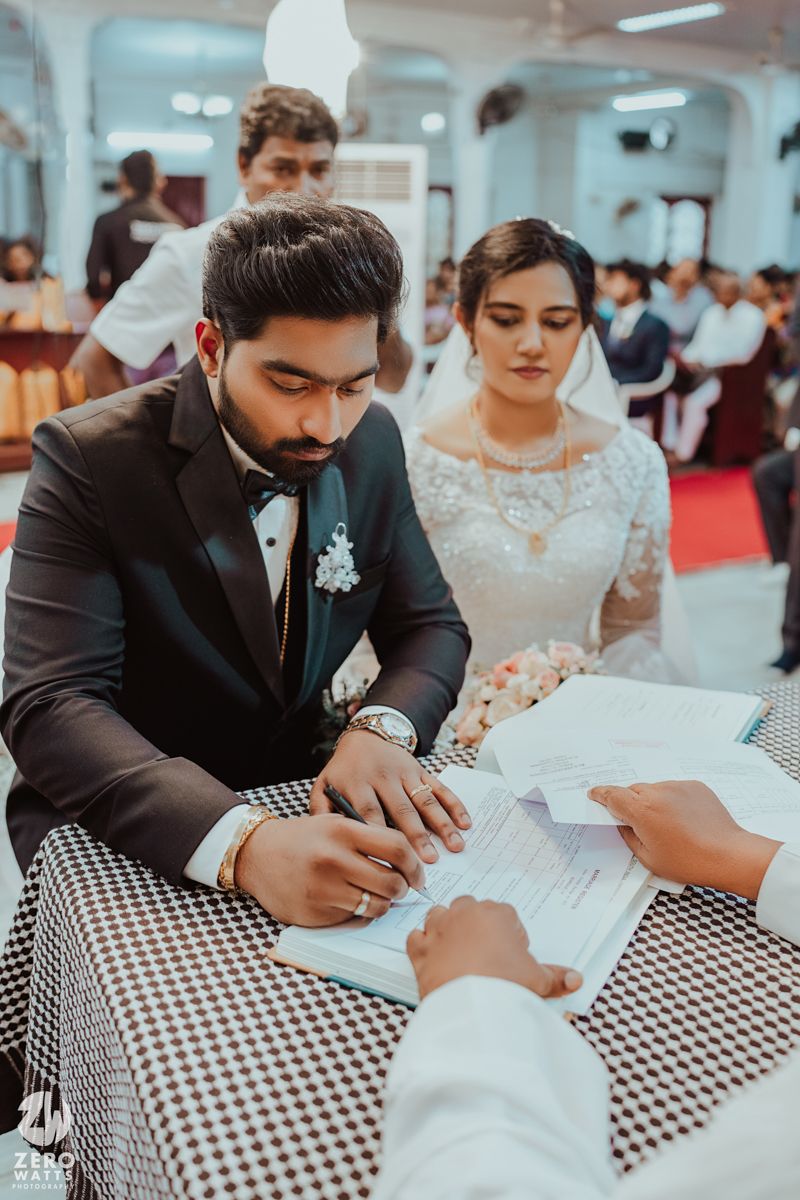 Wedding ceremony signing moment captured at table with black and white checkered tablecloth.