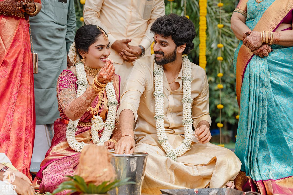 Wedding celebration showing guests in traditional Indian attire gathered under marigold decorations.