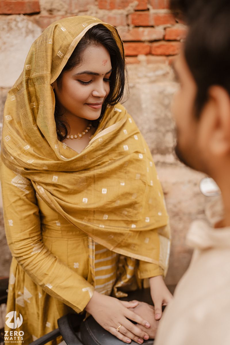 A tender moment captured against brick walls with traditional Indian clothing and jewelry.