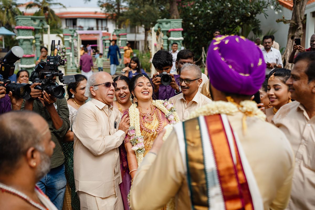 Traditional Indian wedding celebration with guests dancing and celebrating outdoors under palm trees.