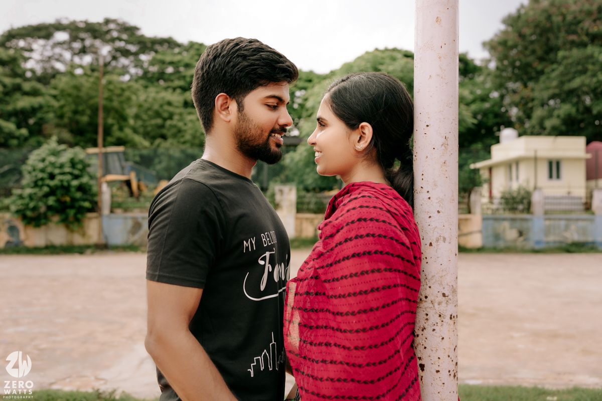 A couple shares an intimate moment outdoors while wearing casual clothing in a romantic photoshoot setting.