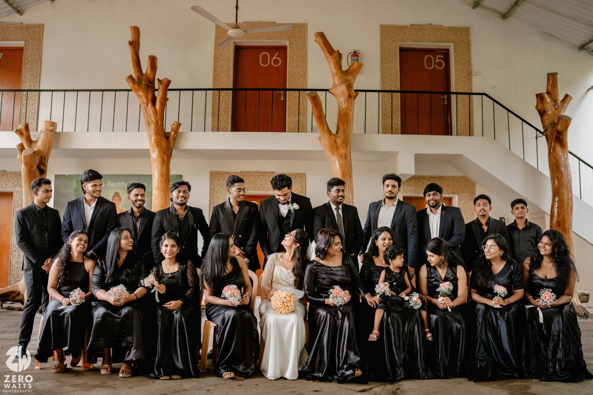 Groomsmen in black suits sit on wooden benches for formal wedding party photos.