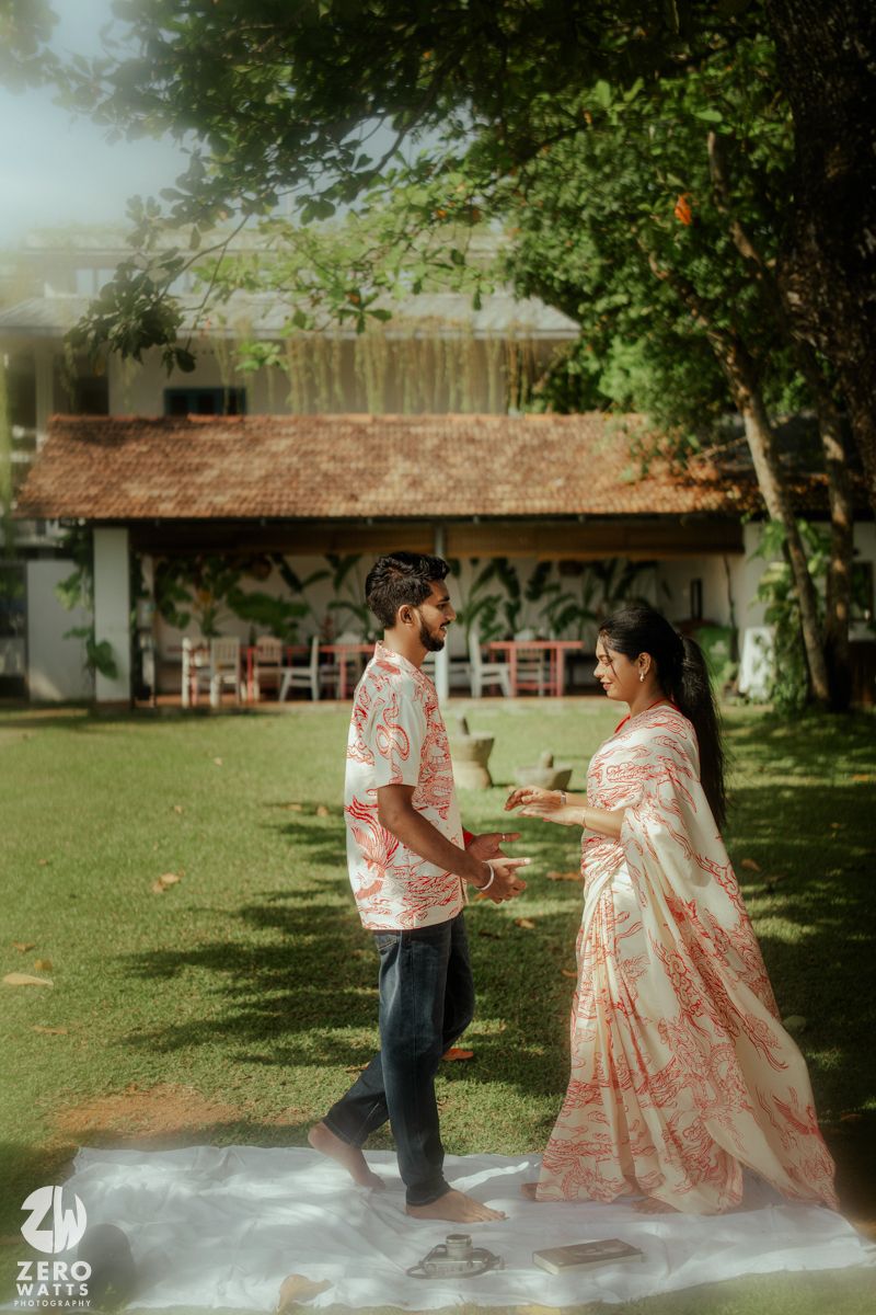 A romantic outdoor photoshoot showing a couple in traditional attire posing together on a grassy lawn.