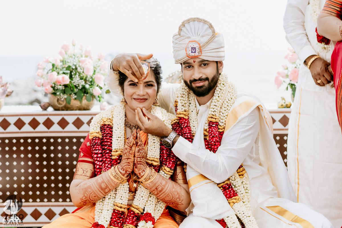Indian bride and groom in traditional wedding attire pose together smiling after their wedding ceremony.