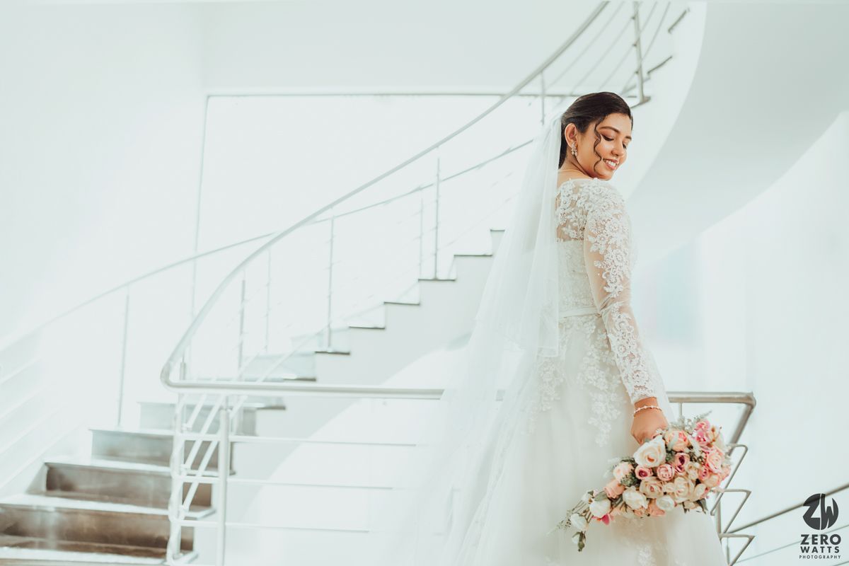 Modern white staircase photoshoot featuring delicate pink floral arrangements and elegant wedding attire.