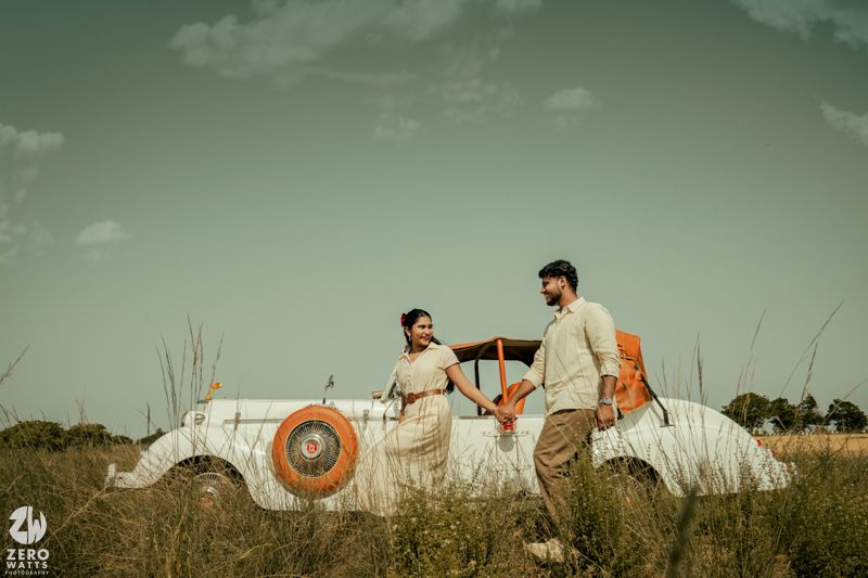 A vintage white classic car parked in a grassy field against a moody green sky.