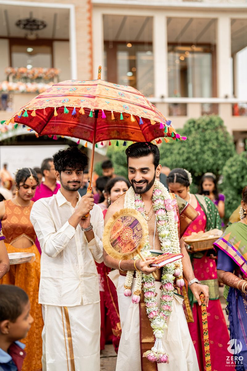 Traditional Indian wedding ceremony with decorative red umbrella and guests in colorful attire during an outdoor celebration.