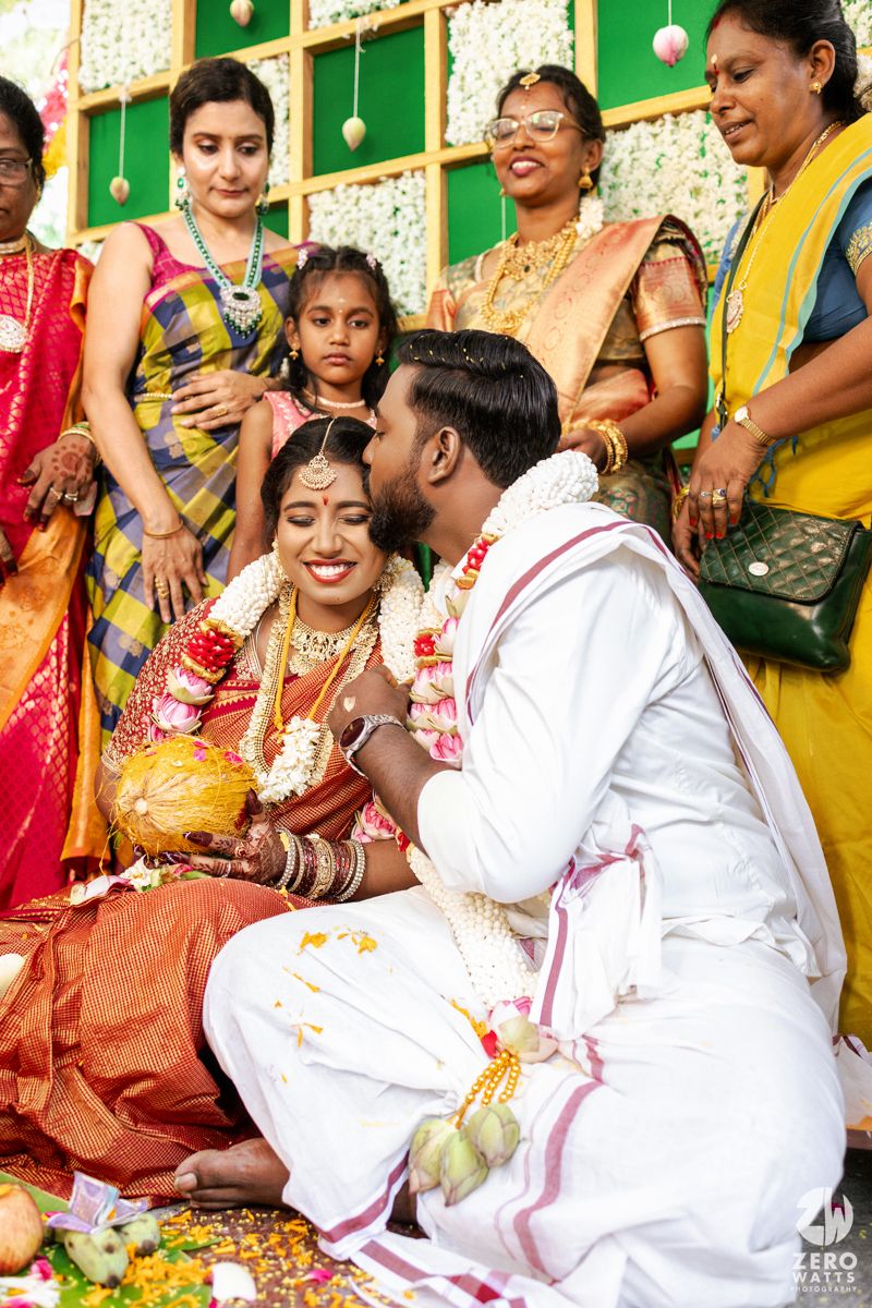 A traditional Indian wedding ceremony shows participants in white and colorful saris performing rituals and customs.
