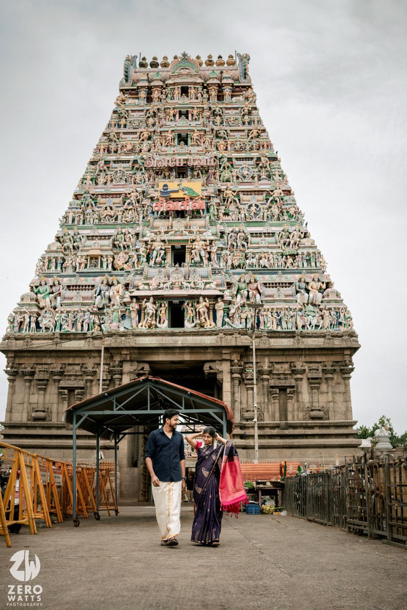 Traditional South Indian temple architecture with ornate gopuram and detailed stone carvings against cloudy sky.