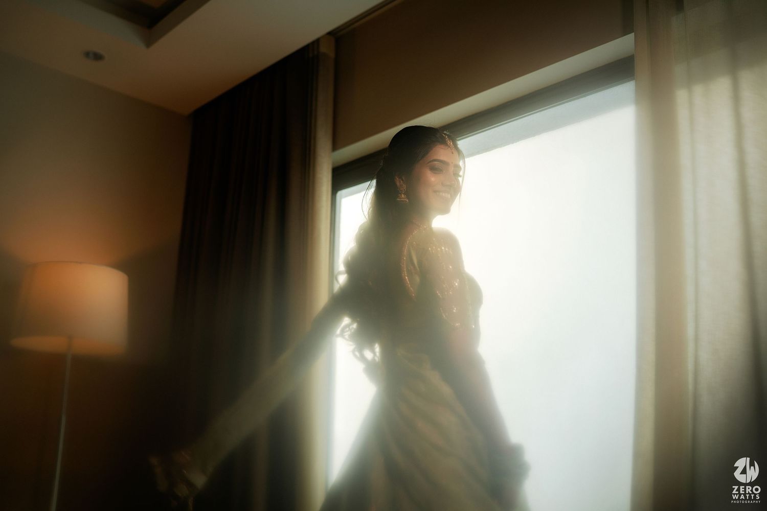 A moody silhouette of a figure standing by a window with dramatic backlighting creating an atmospheric scene.
