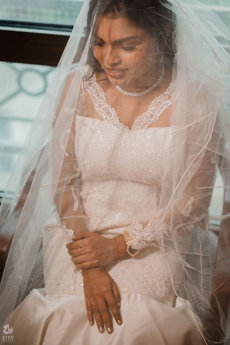 A close-up portrait of a bride wearing a delicate lace veil and elegant white wedding gown.