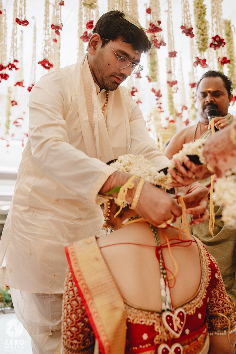 Traditional Indian wedding ceremony shows the groom applying sindoor to the bride's forehead during a ritual.