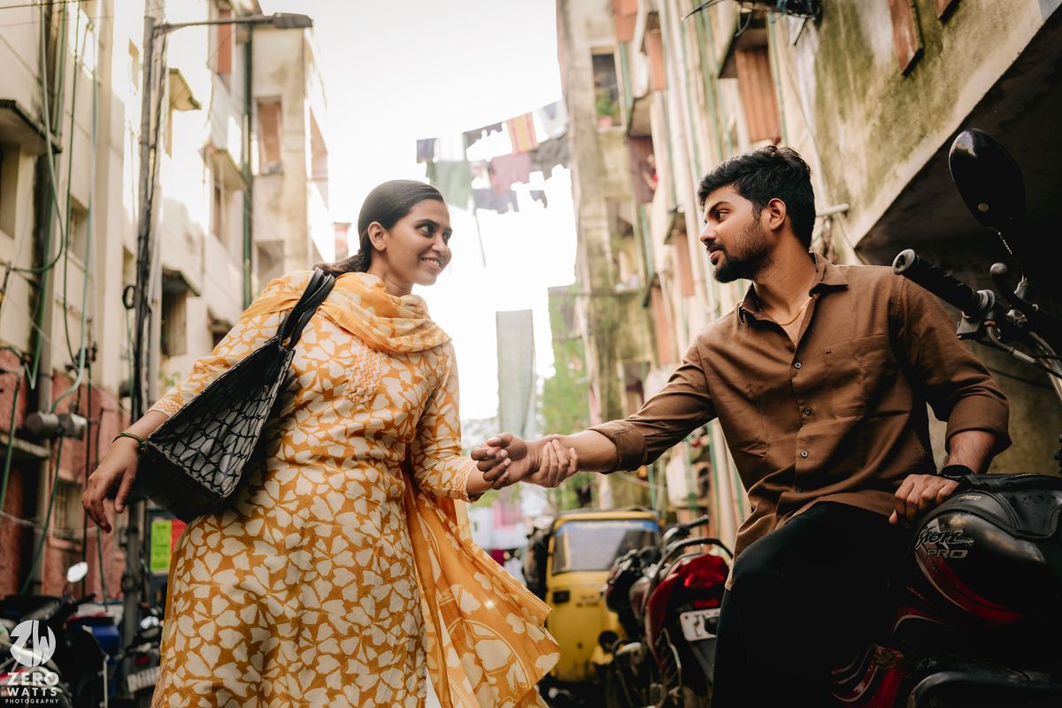 A couple shares a playful moment together in a narrow urban alleyway.