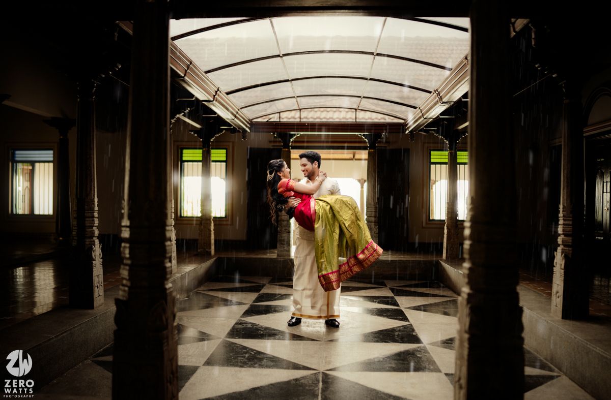 Couple sharing a romantic embrace in a grand Indian palace corridor with checkered floors and ornate architecture.