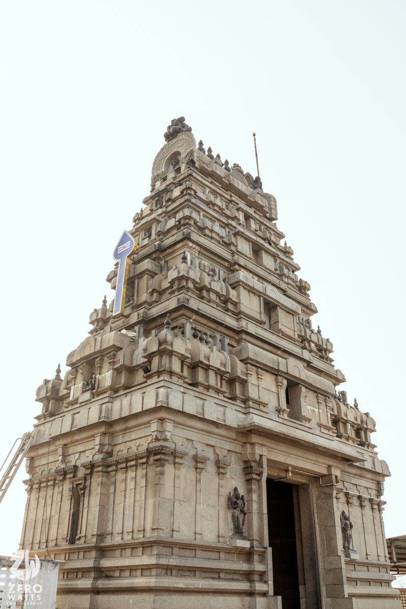 Ancient South Indian Hindu temple tower (gopuram) with intricate stone carvings rising against a clear sky.