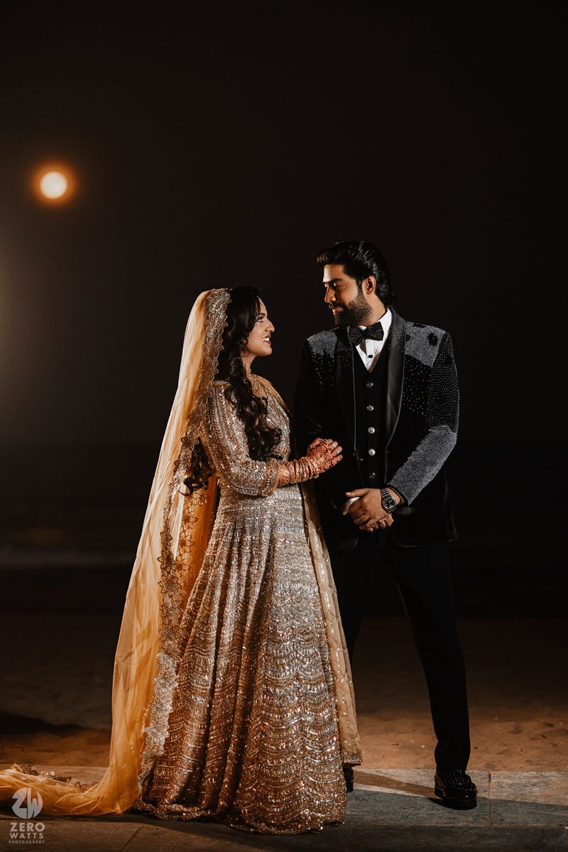 A romantic nighttime photoshoot featuring a couple in traditional South Asian wedding attire under a glowing moon.