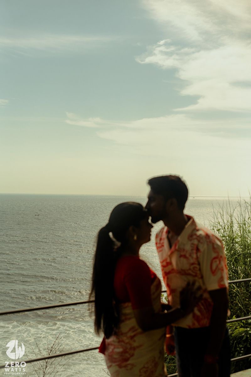 Silhouetted couple shares intimate moments against scenic ocean backdrop during sunset photoshoot.
