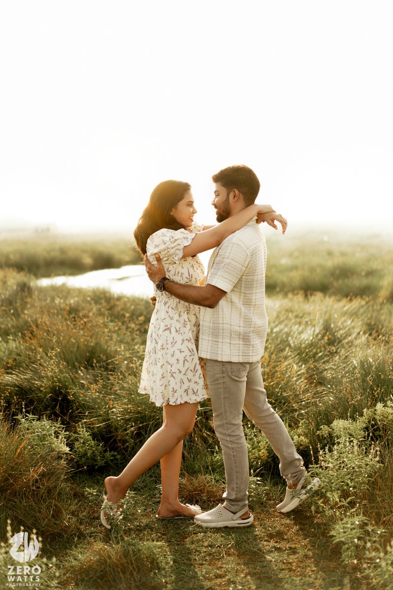 A couple dances playfully together in a sunlit meadow wearing casual summer outfits.