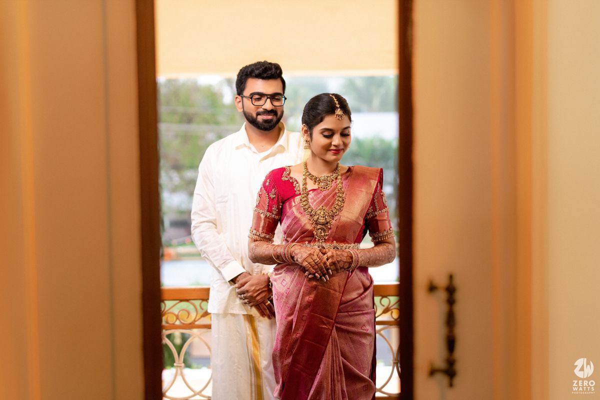South Indian bride and groom in traditional attire standing together on a balcony.