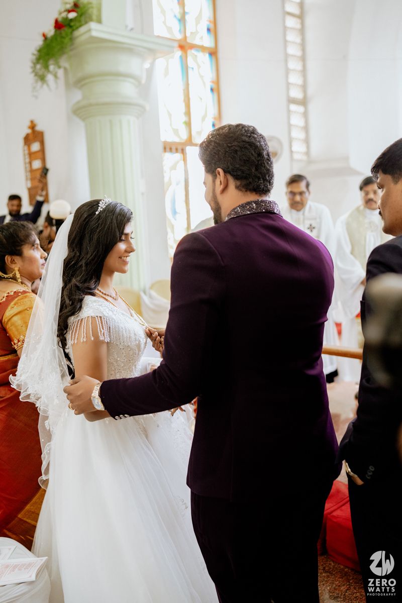 Bride and groom holding hands at church altar during wedding ceremony, bride wearing white gown and veil.