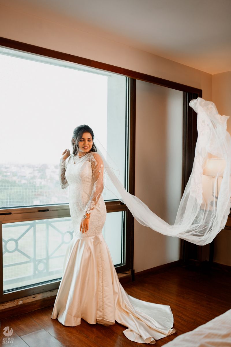 A sequence of flowing white wedding dress movements by a window in natural light.