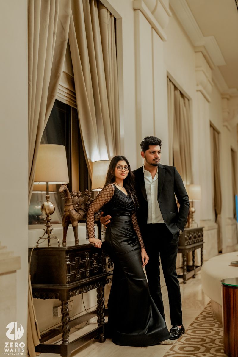 Stylish couple walks through luxurious hallway with cream curtains and classic decor.