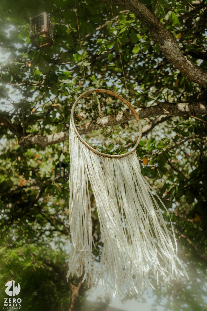 Decorative white fabric streamers hang from tree branches in a lush green outdoor setting creating a dreamy atmosphere.