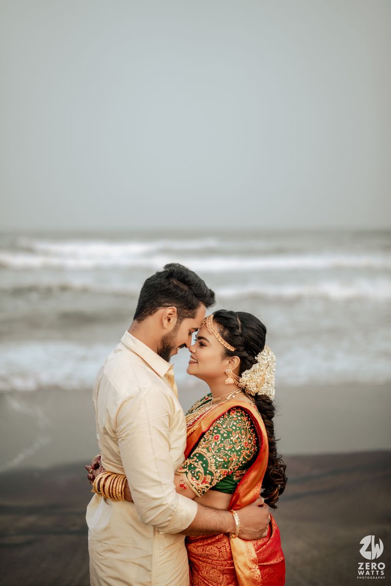 South Indian bride and groom sharing an intimate moment by the ocean waves on wedding day.