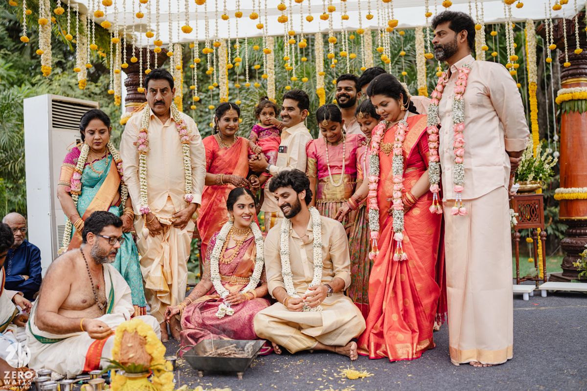 Traditional Indian wedding celebration with guests in colorful saris and formal attire under yellow decorations.