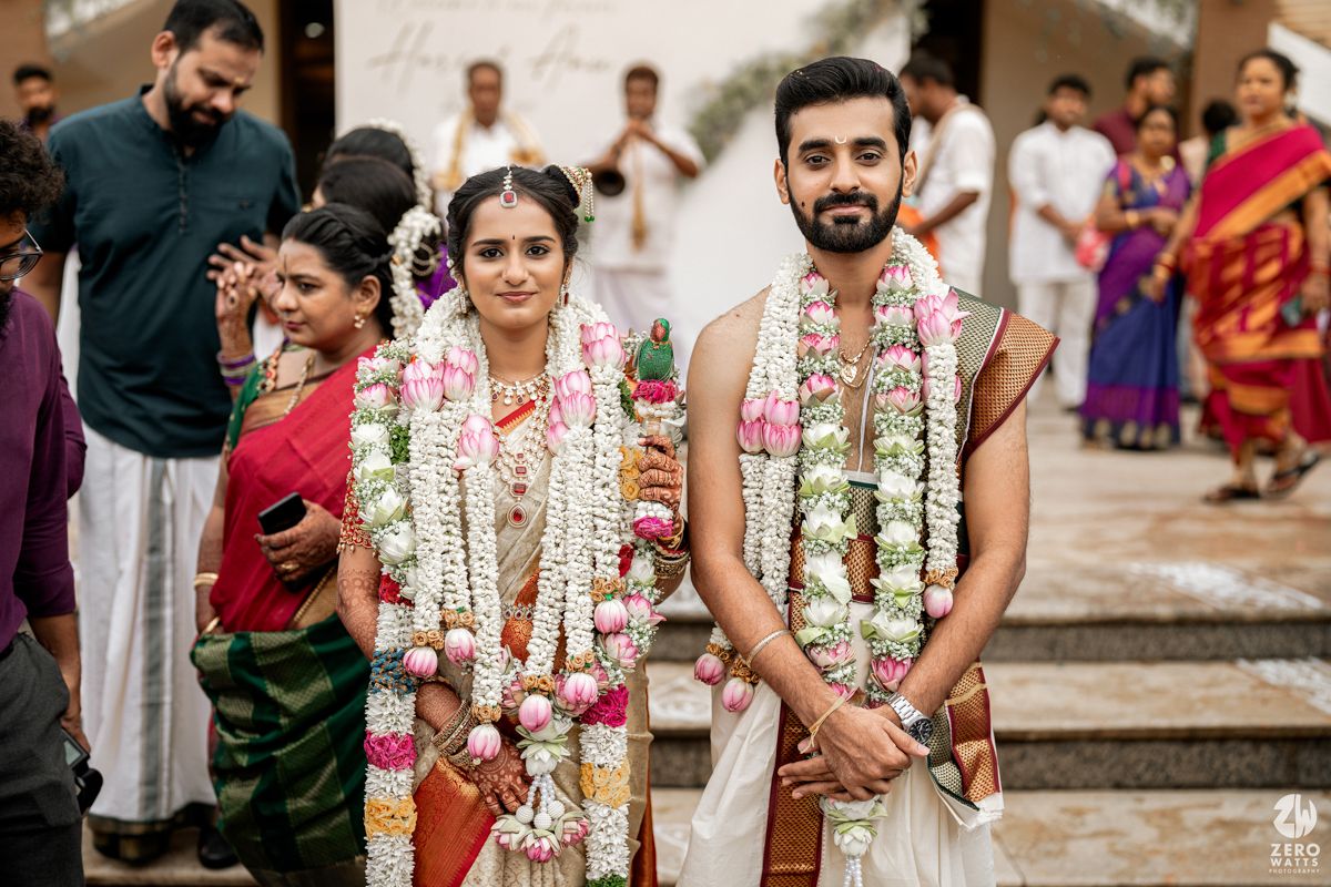 Traditional South Indian wedding couple wearing floral garlands and traditional attire during ceremony.