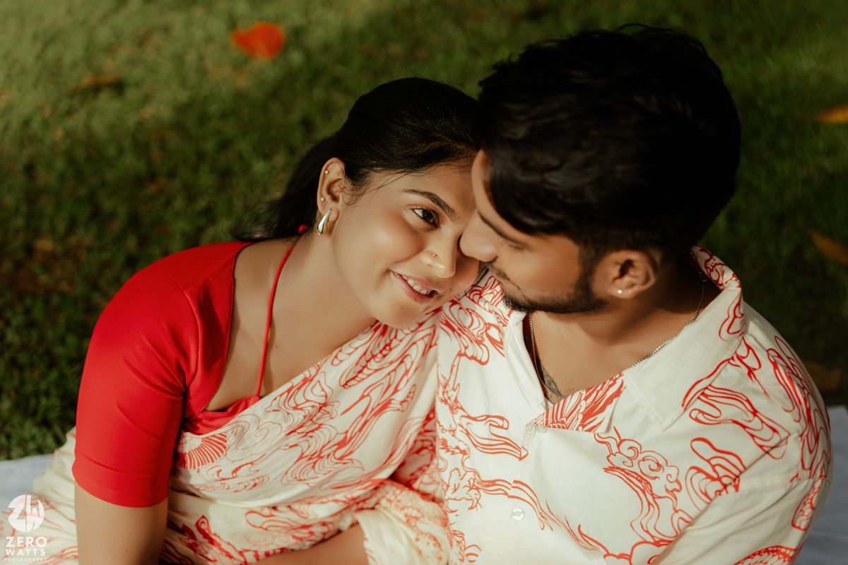 A couple in coordinated red and white outfits share intimate moments together in a romantic outdoor photoshoot.