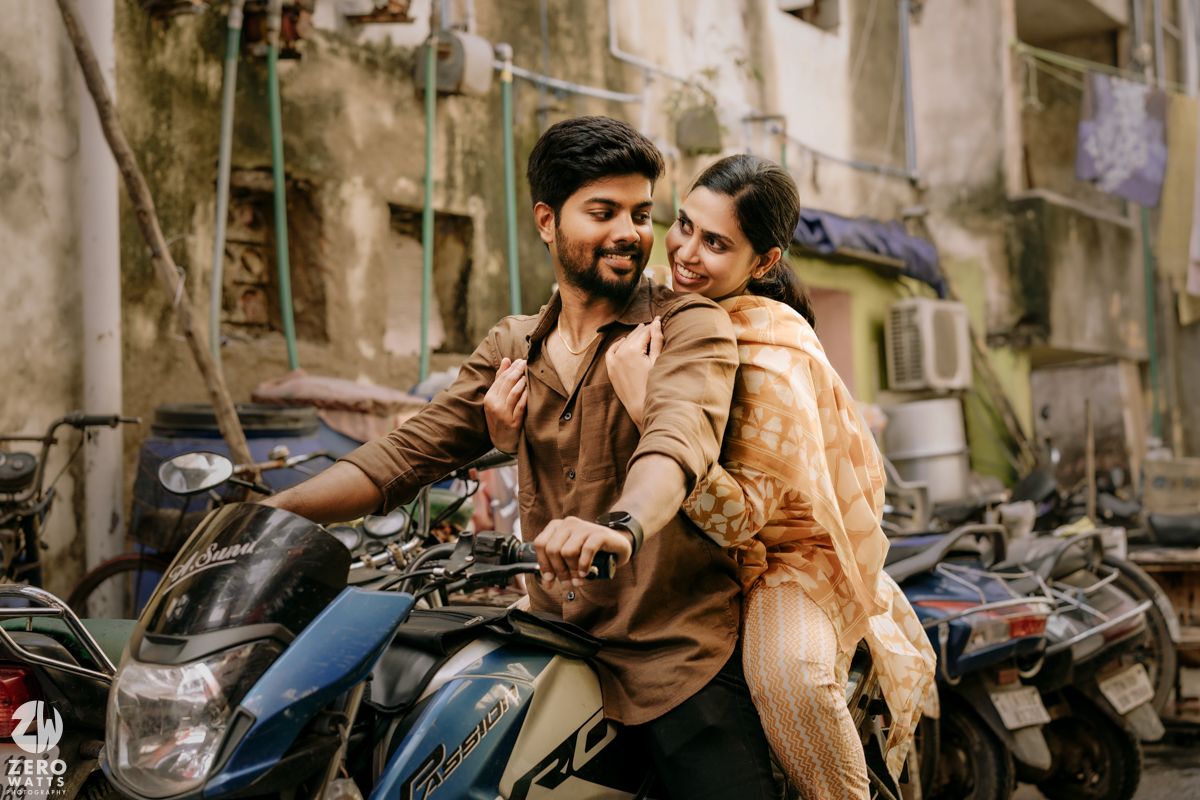 A couple shares a joyful moment together on a motorcycle parked on a city street.
