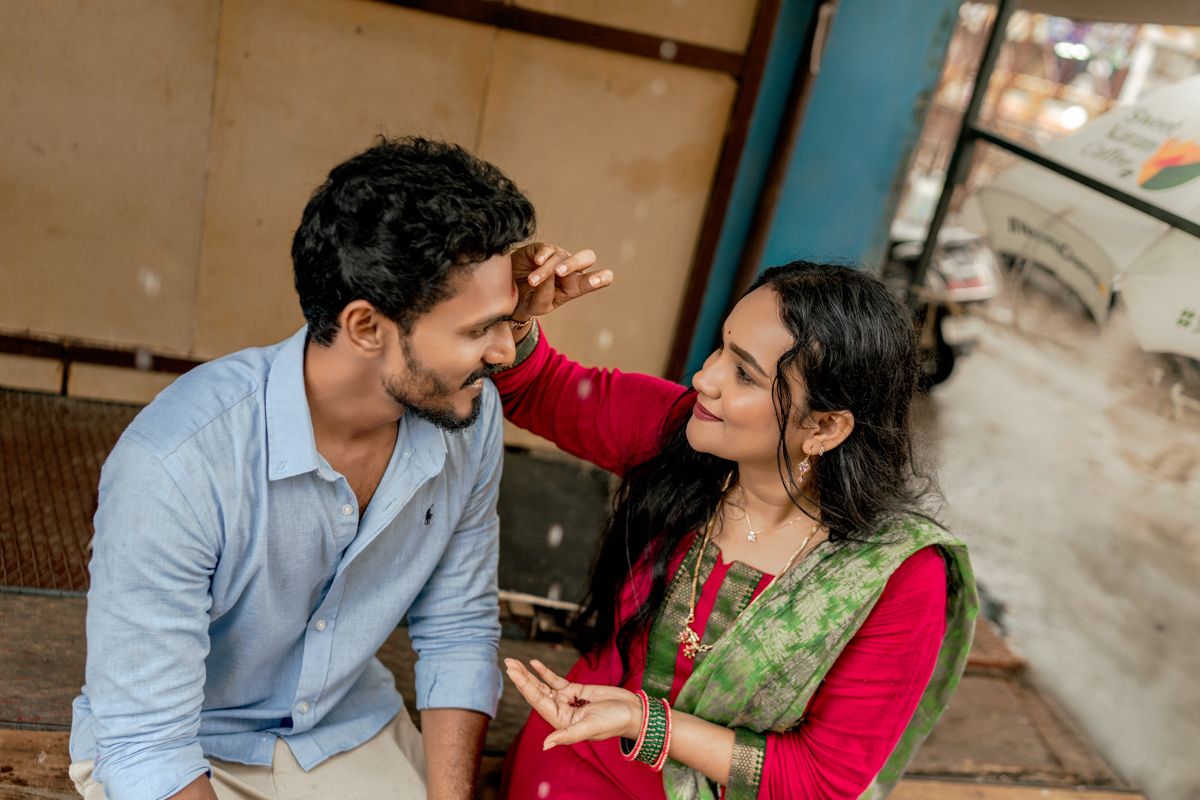 Couple sharing a playful moment together on a porch with striped awning overhead.