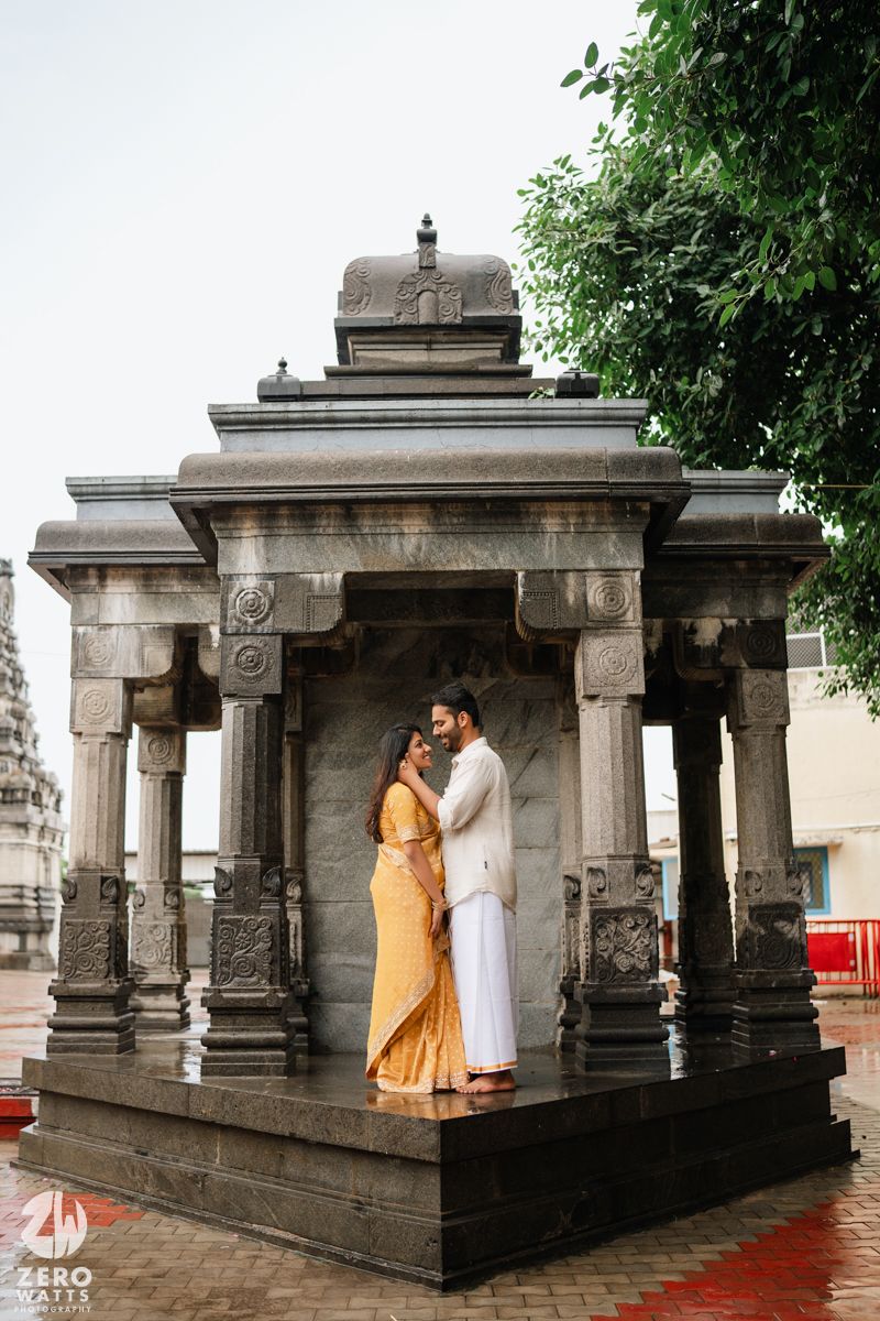 A couple shares intimate moments at a traditional Indian stone temple with ornate pillars and architecture.