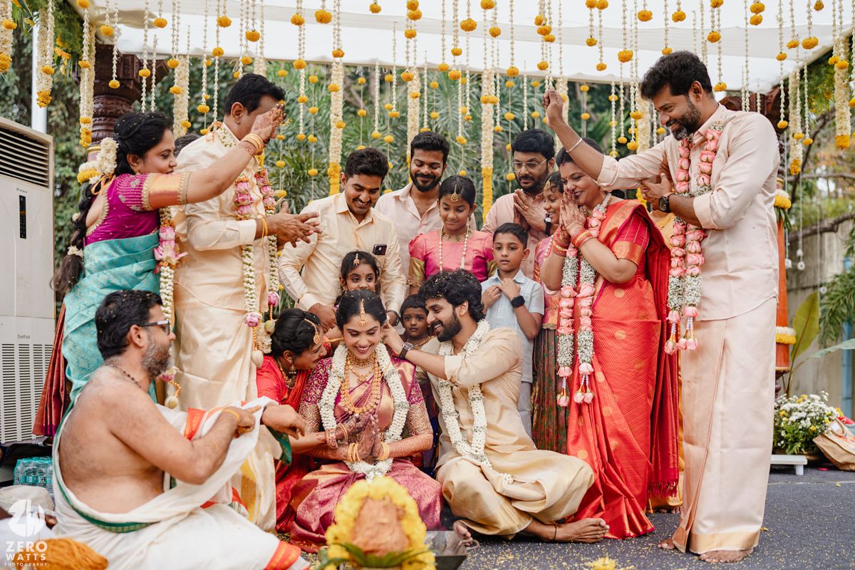 Festive Indian wedding ceremony with hanging yellow marigold decorations and traditional attire.
