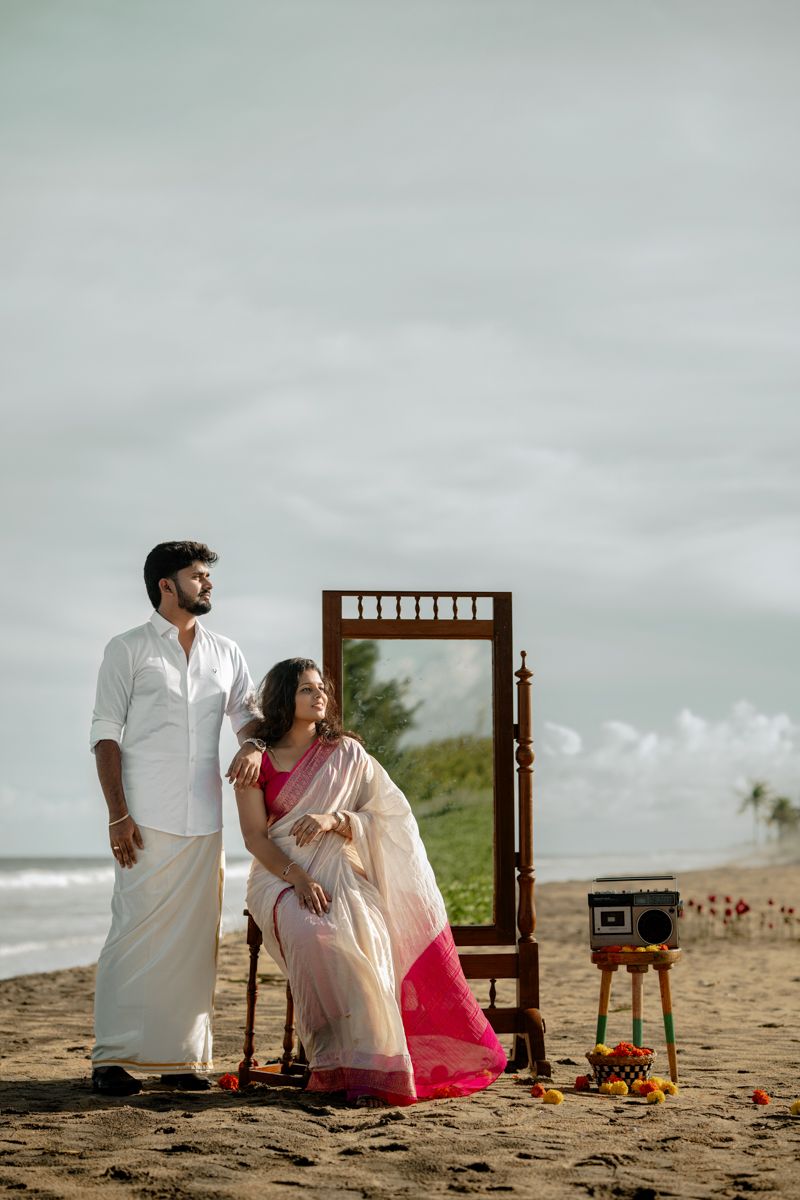 A romantic beach scene with a wooden chair and decorative setup against a cloudy sky.
