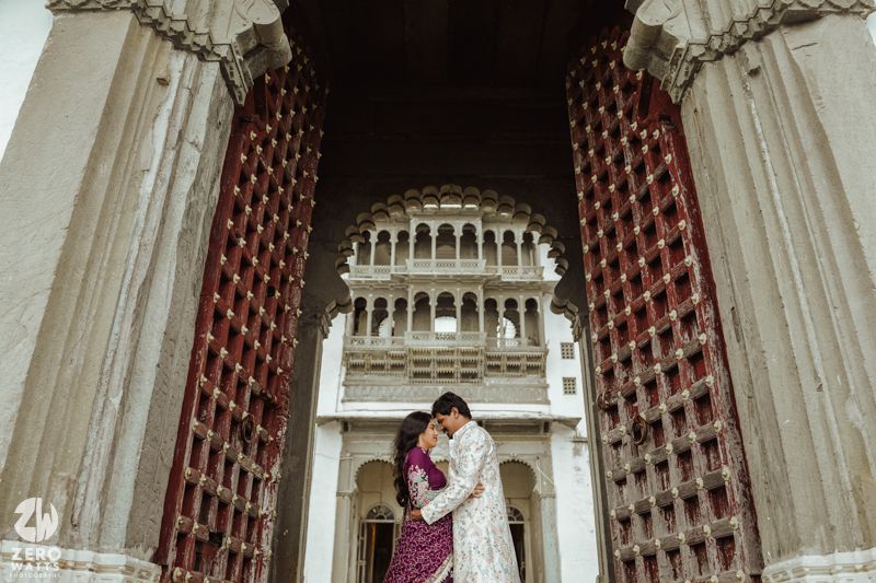 Romantic moment framed by grand carved doorway at historic Udaipur palace.