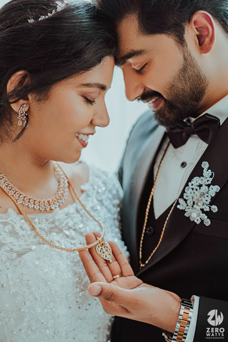 Close-up shot of couple in wedding attire sharing intimate moment while looking at jewelry.