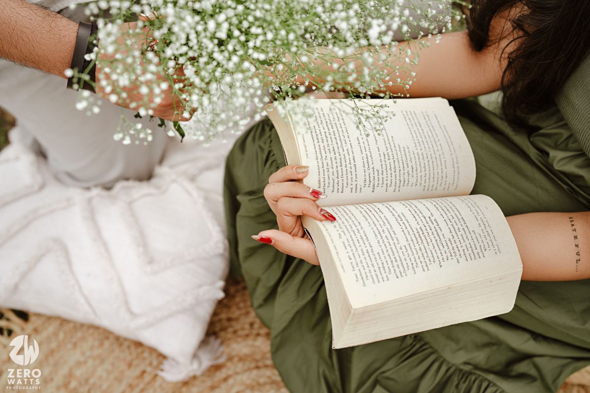 Close-up of hands holding an open book with baby's breath flowers laid across the pages.