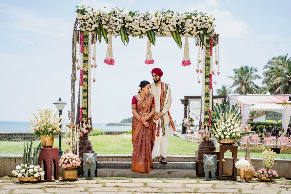 Beachside wedding venue decorated with white floral arrangements and hanging elements.