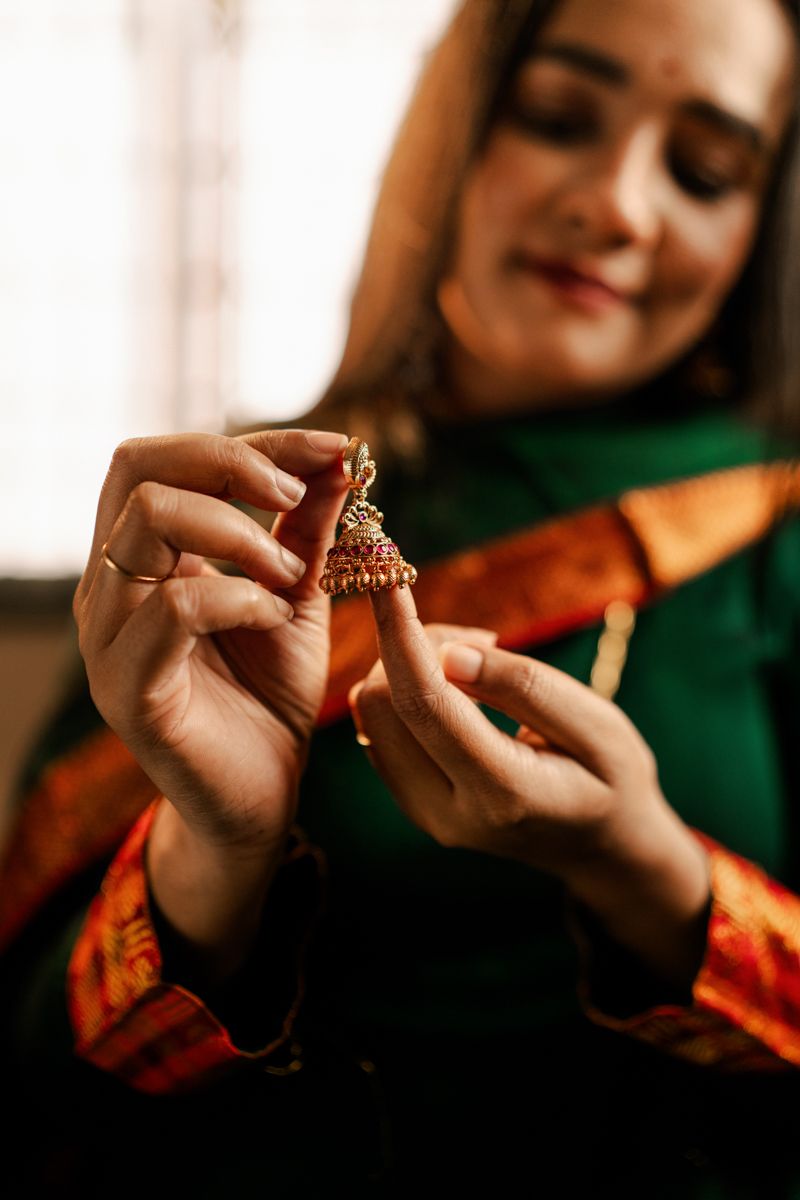 Close-up shots of hands holding and examining traditional Indian jewelry against a blurred background.