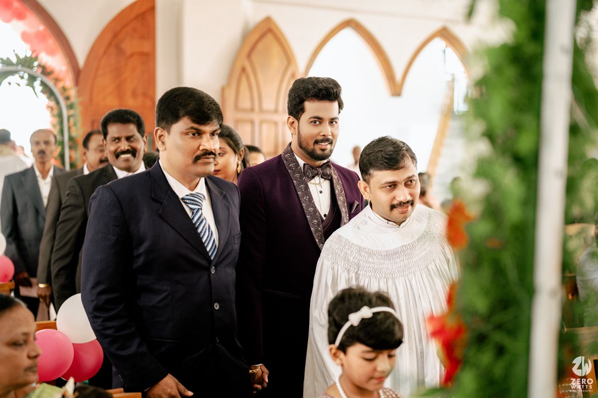 Men in formal attire at an Indian wedding ceremony inside a decorated church.