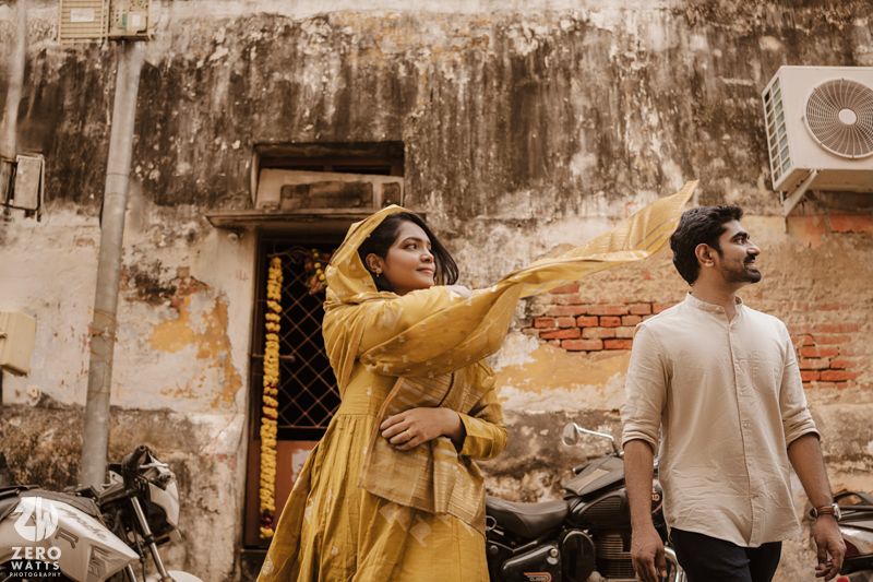 Couple in casual attire dancing and embracing against a rustic brick wall background.