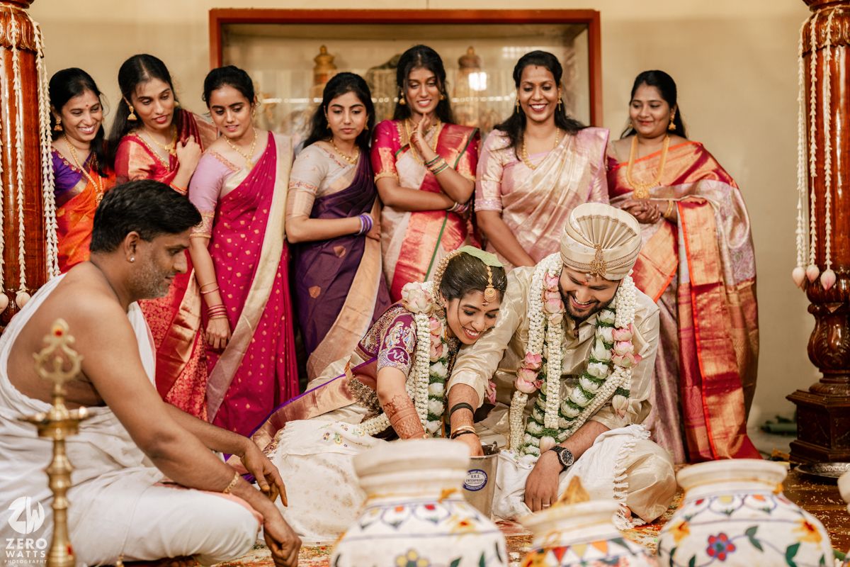 Traditional Indian wedding ceremony with participants seated on floor during ritual proceedings.