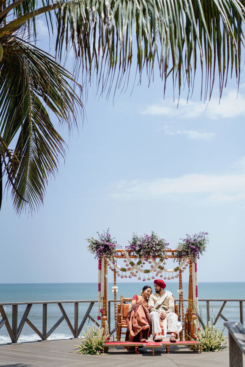 Beachfront wedding ceremony setup with bamboo arch and ocean view.