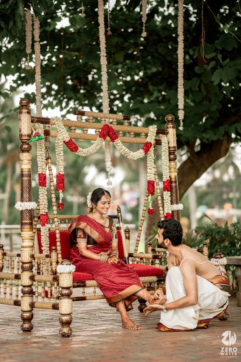 Decorated wooden swing with floral garlands and couple in traditional South Indian wedding attire.