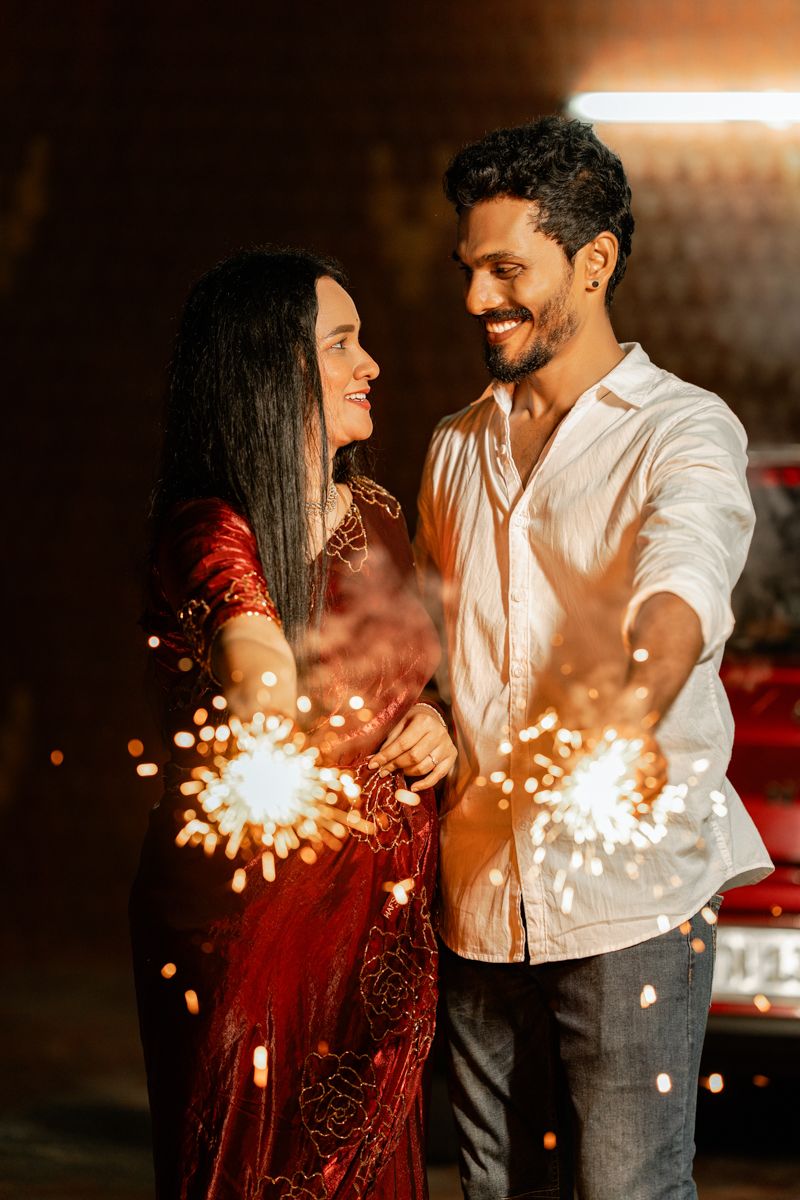 A couple in red and white outfits plays with sparklers creating beautiful light patterns in the dark.