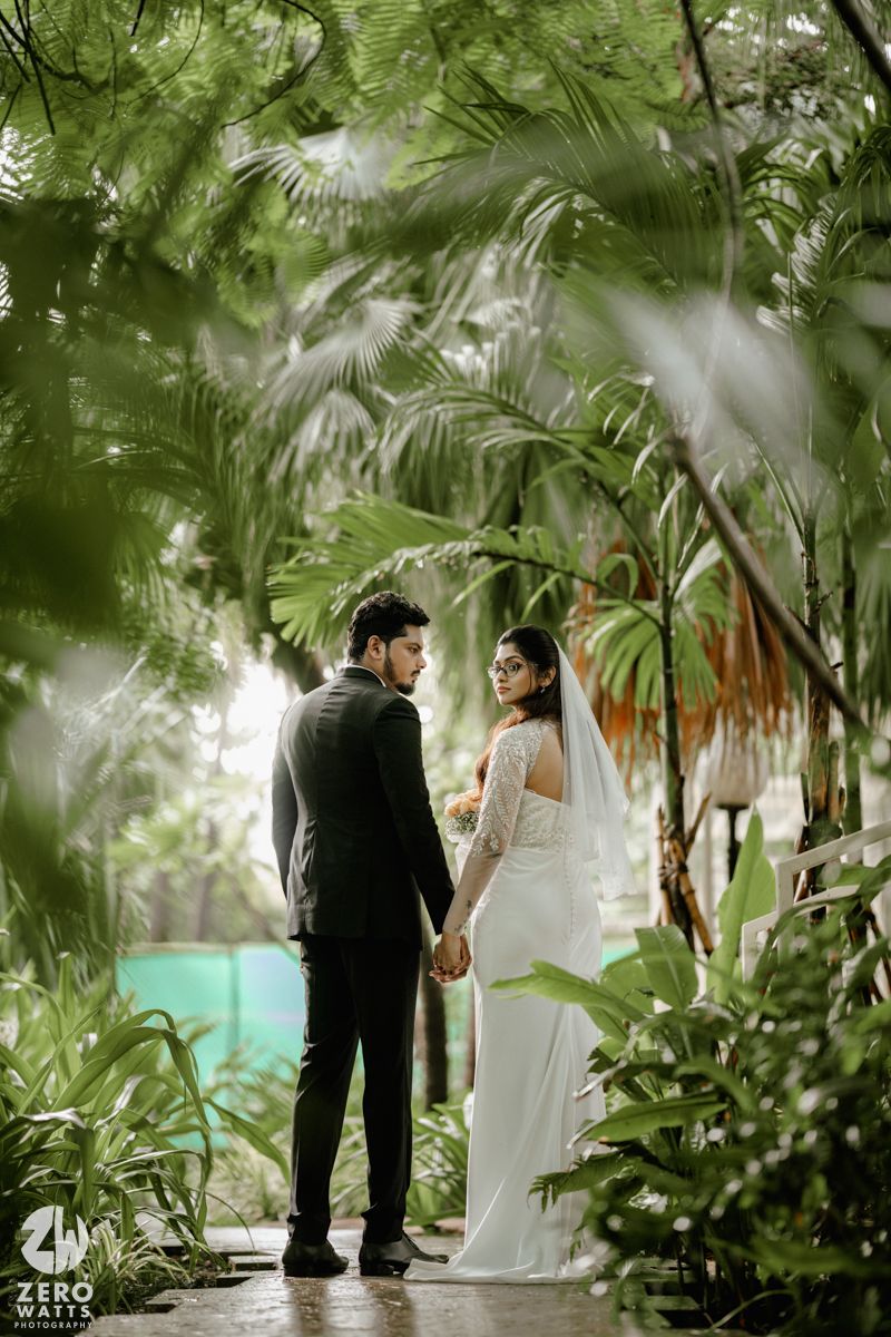A couple shares an intimate moment in a lush tropical garden setting during their wedding ceremony.