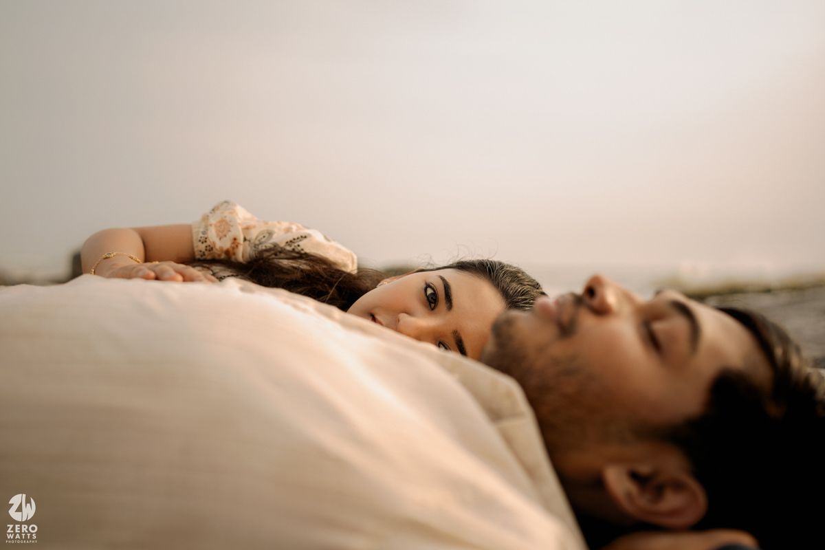 Dreamy portrait on white sheets with soft natural lighting creating ethereal atmosphere.